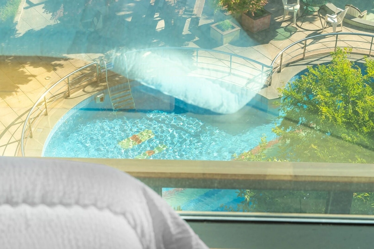 Un espace piscine agrémenté d’une barrière en verre, d’un escalier et offrant une vue sur le paysage environnant.