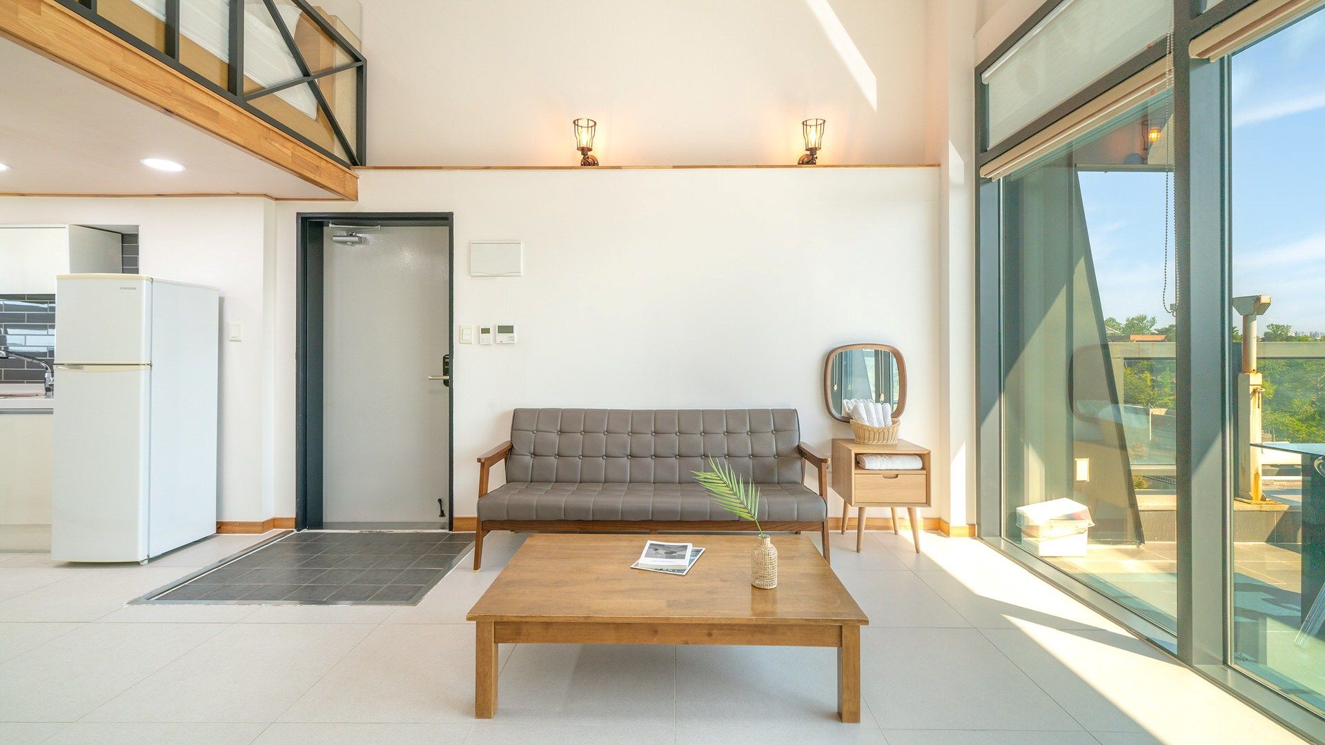 Un salon moderne avec un canapé, une table basse et une petite table d’appoint sur laquelle se trouve une lampe.
