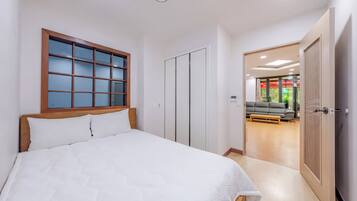 A bedroom with a bed, a wardrobe, and a view into a living area.