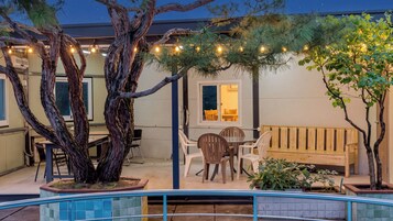 Un patio al aire libre con un banco de madera, sillas y una mesa de comedor.