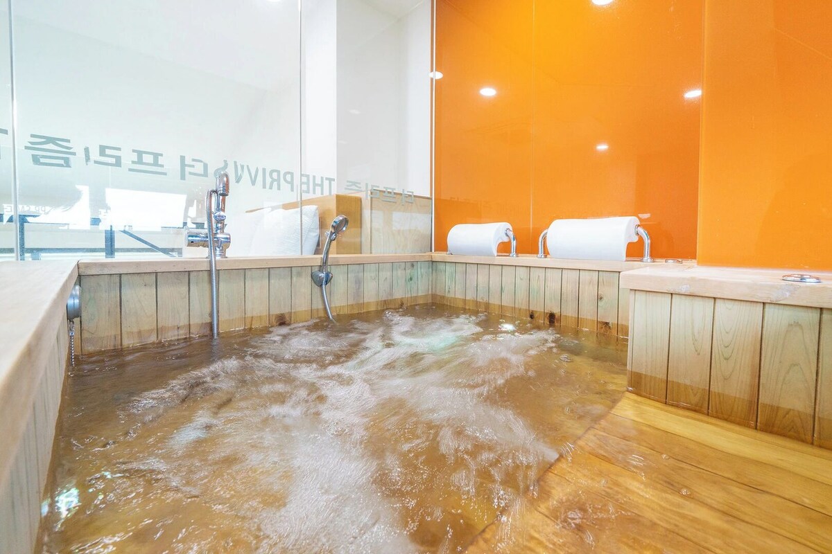 Un bain à remous en bois équipé de deux robinets et de deux rouleaux de papier toilette.