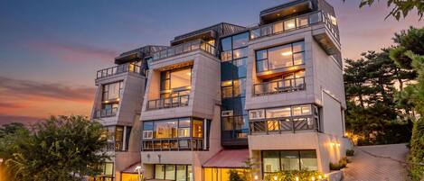 Ein mehrstöckiges Hotel mit Balkonen, großen Fenstern und Außenbeleuchtung.