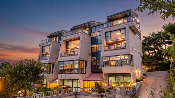 A multi-story hotel with balconies, large windows, and outdoor lighting.