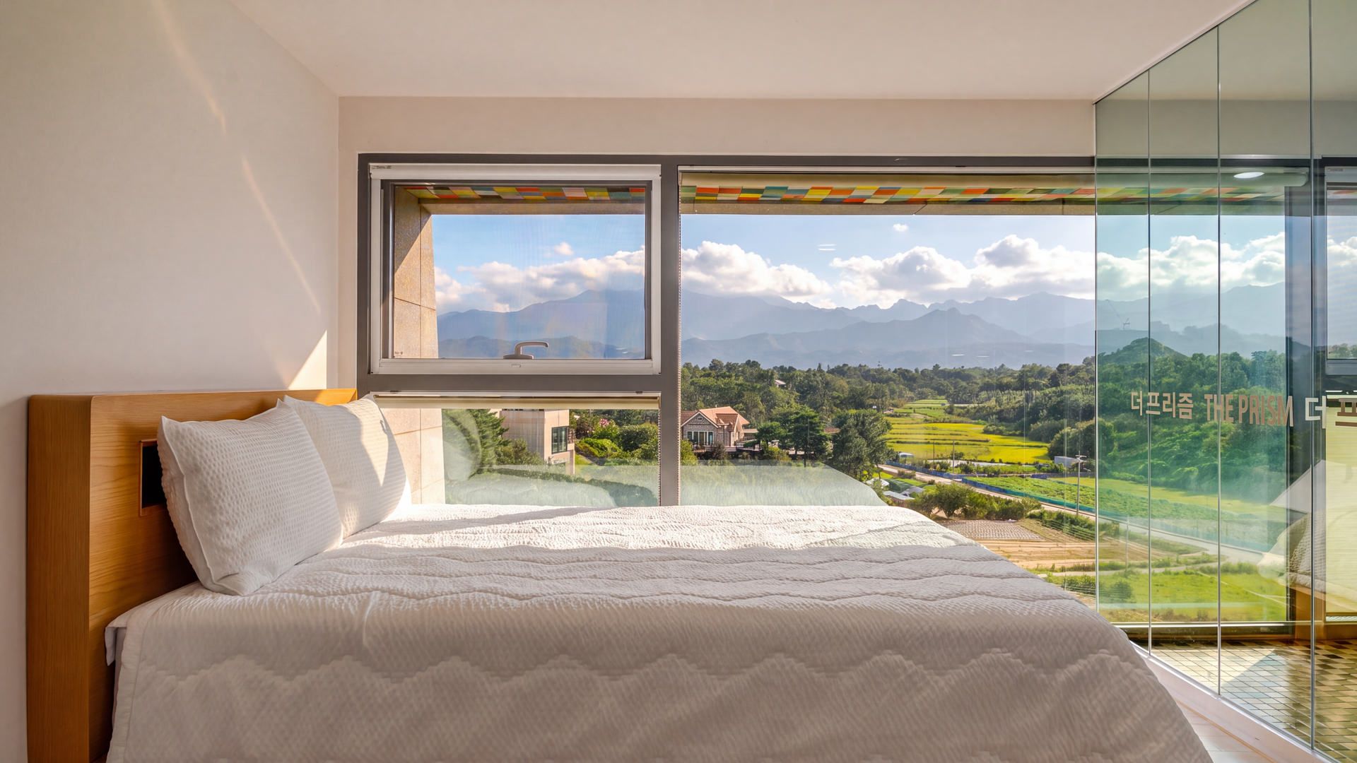 A bedroom with a large window overlooking a scenic landscape.
