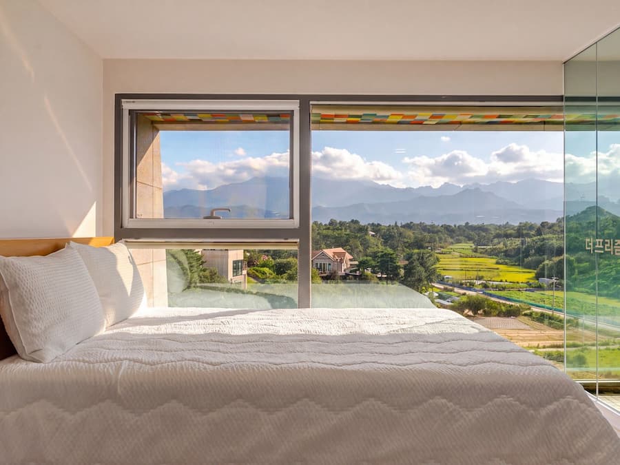 A bedroom with a large window overlooking a scenic landscape.