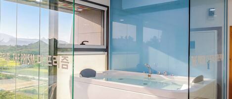 Un baño moderno con una bañera grande, cabina de ducha de vidrio y vistas a un paisaje montañoso.