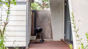 Un petit espace extérieur avec un barbecue portable installé sur une terrasse en bois.