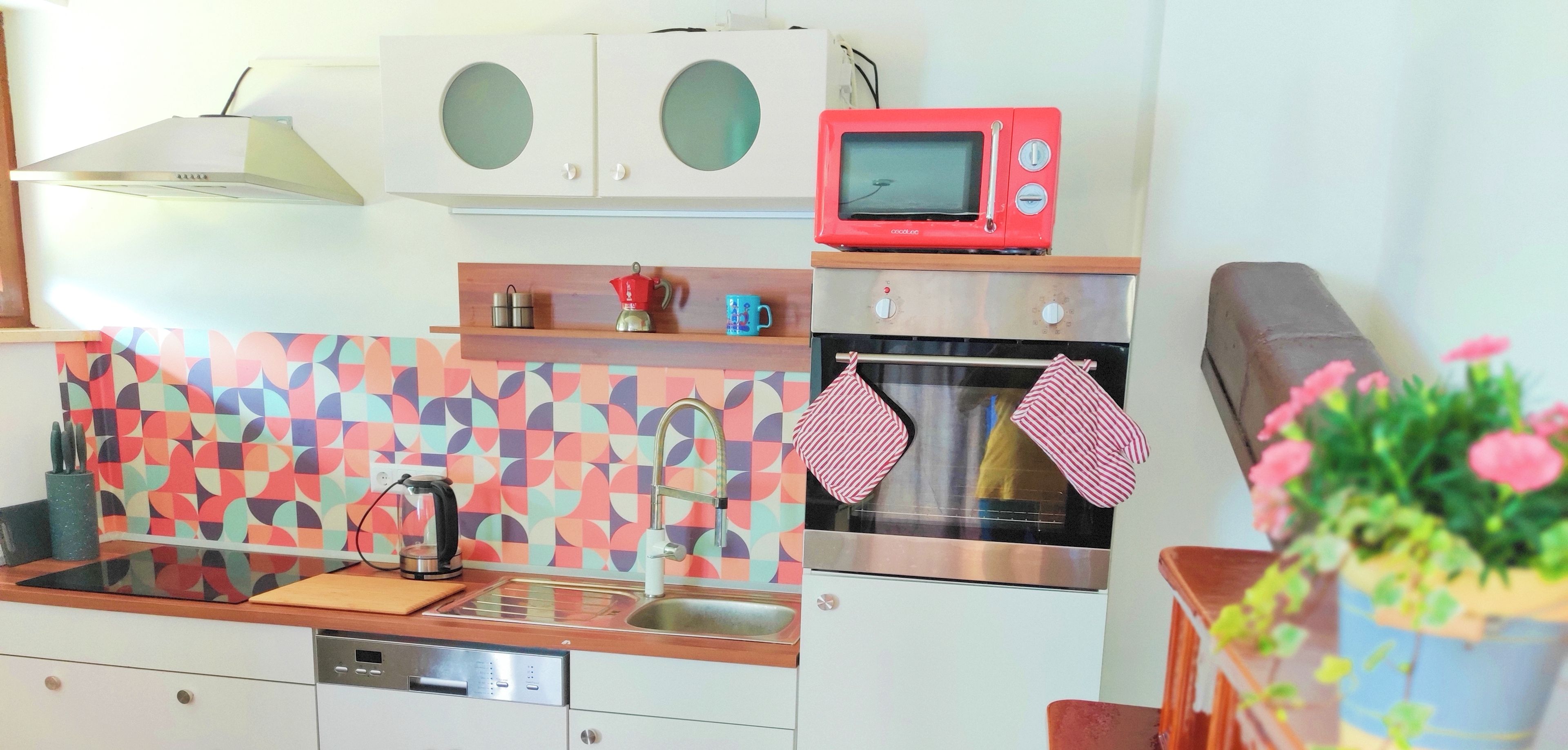 Une cuisine compacte équipée d’un four à micro-ondes, d’un four et d’un crédence moderne.
