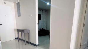 A hallway with a door on the left, a small table, and a dark-colored bag in the background. - 2 Bed-Sleeps 5-Private Garden-Free Parking (Portmore)