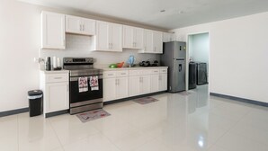 A modern kitchen with white cabinets, stainless steel appliances, and a tiled floor. - 2 Bed-Sleeps 5-Private Garden-Free Parking (Portmore)