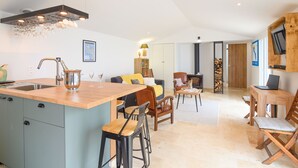 Une cuisine moderne dotée d’un îlot central, de tabourets de bar et d’un coin repas avec une table et des chaises en bois.