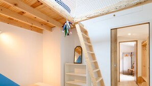 Une chambre avec un lit superposé, une échelle en bois, un miroir et une armoire.