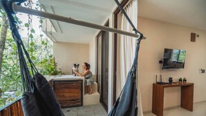 A balcony with a hammock, a person petting a dog, and a TV on a wooden stand. - Tulum Getaway+Pool+Office Area+Gym (Tulum)
