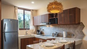 A modern kitchen with a built-in refrigerator, a microwave, and a dining area with a table set for two. - Tulum Getaway+Pool+Office Area+Gym (Tulum)