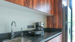 A modern kitchen with dark wood cabinets, a stainless steel sink, and a built-in microwave. - Elegant Studio in Holistika: Your Tulum Sanctuary (Tulum)