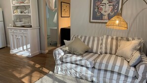 Un salon avec un canapé à rayures, un meuble blanc et un tableau accroché au mur.