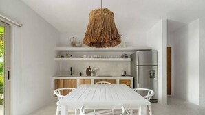 Una cucina moderna con mobili bianchi, un frigorifero in acciaio inossidabile e una lampada a sospensione in fibra.