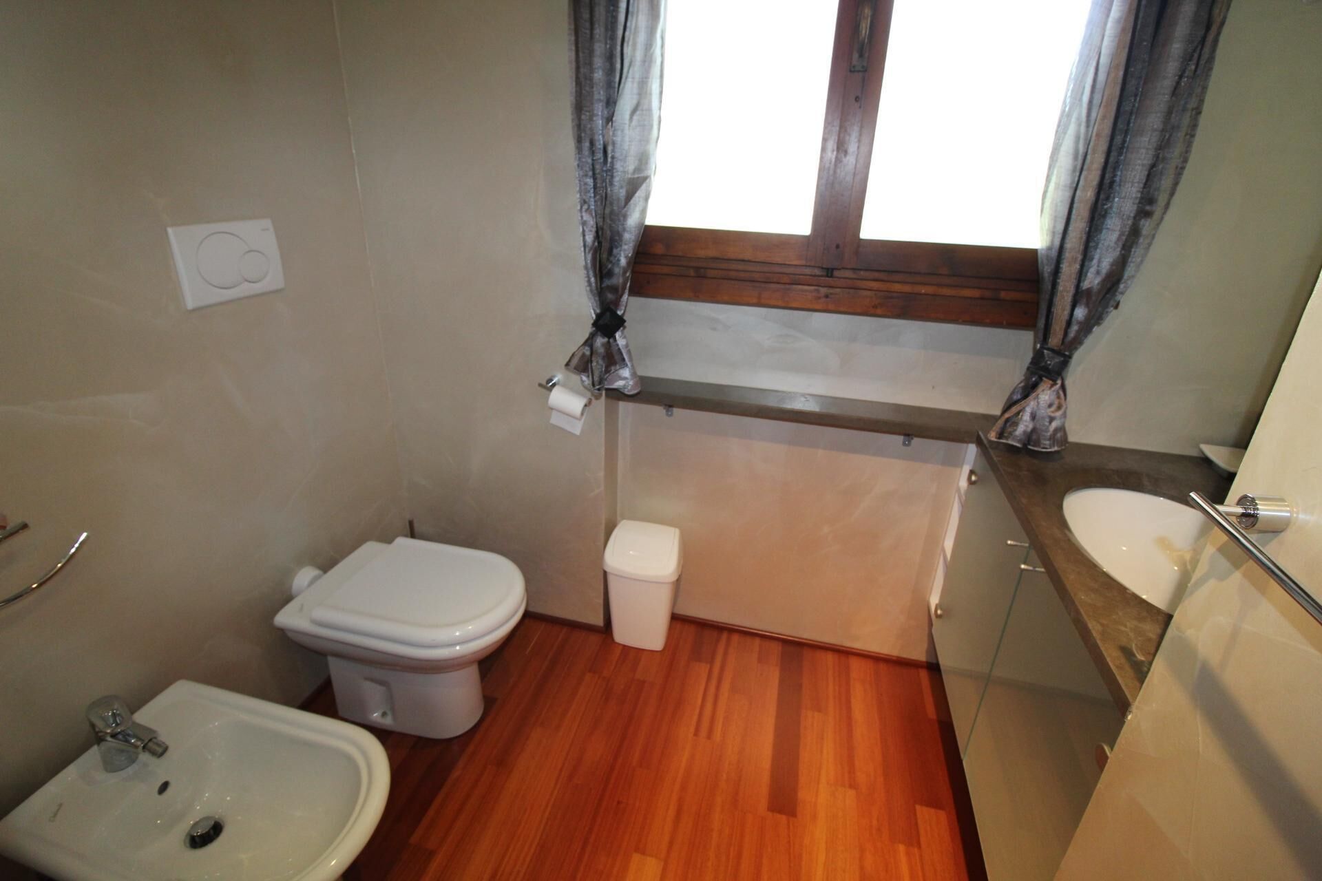 Et lille badeværelse med toilet, pissoir og vask.