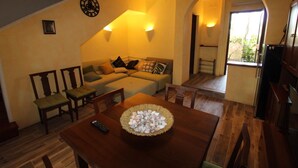 A cozy living room with a sofa, chairs, a wooden table, and a bowl of seashells.