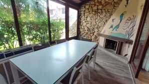 A dining area with a stone wall and a mural, a fireplace, and a view of greenery outside.