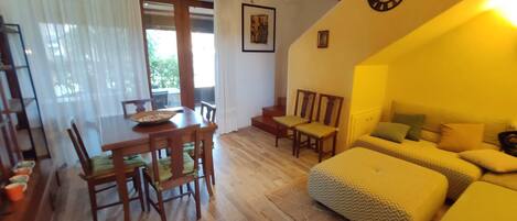 A cozy room with a wooden dining table, chairs, a sofa, and a bed.