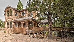 A two-story stone house with a covered porch and a fenced deck. - Bridgeway House (Duck Creek Village)