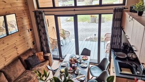 Viehättävä mökki, jossa on ruokailutila, sohva ja keittiö.