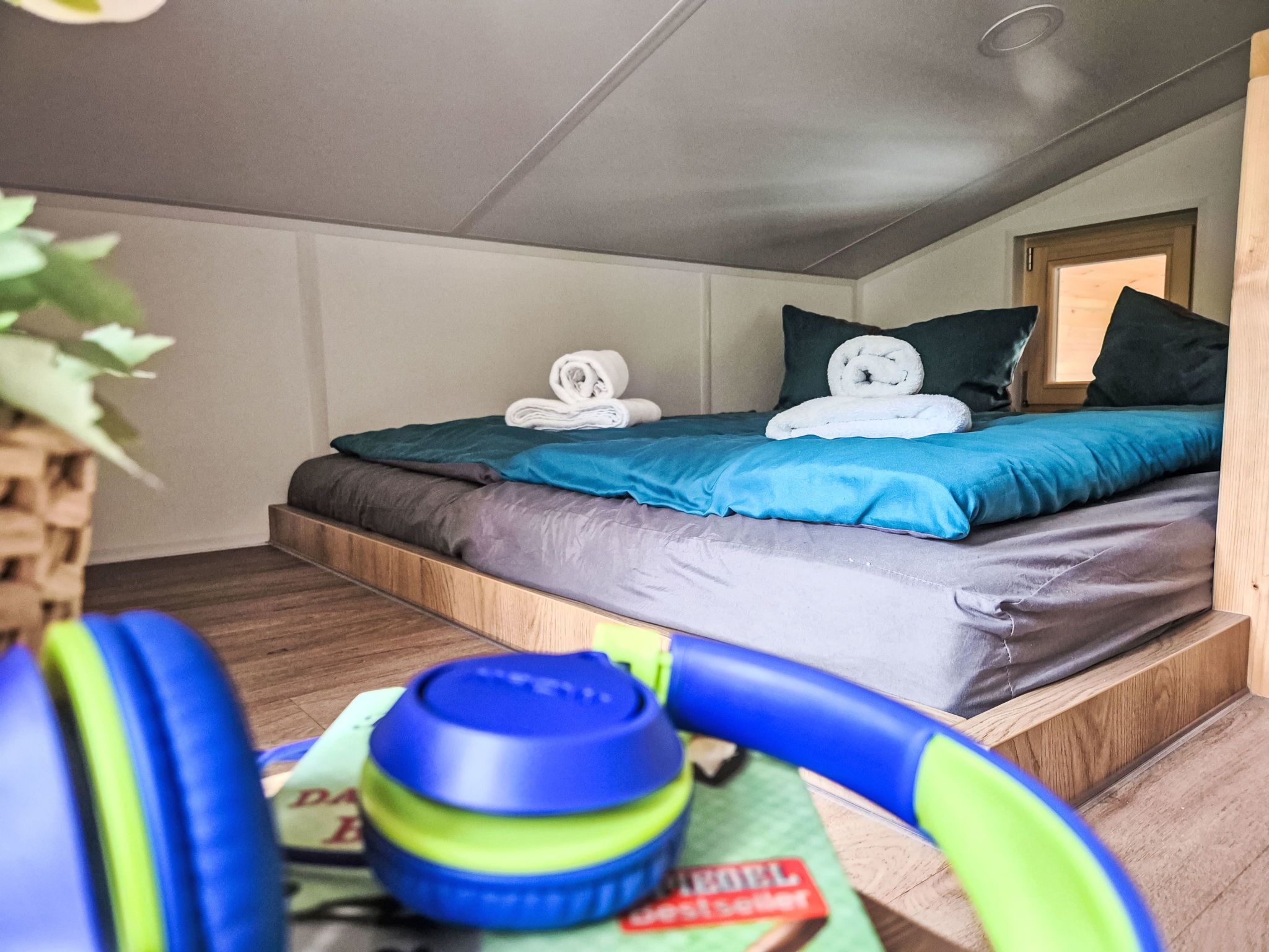 Una habitación pequeña y acogedora con una cama, una mesita y una planta.
