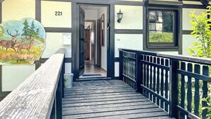 A wooden deck leading to a building with a number '221' on the wall.