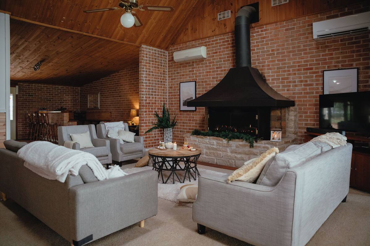 A cozy living room with a fireplace, sofas, and a TV.