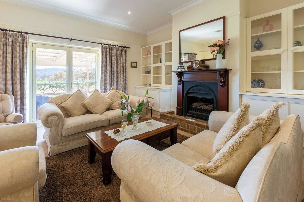A living room with a sofa set, a coffee table with a vase, a fireplace, and built-in shelving with decorative items.