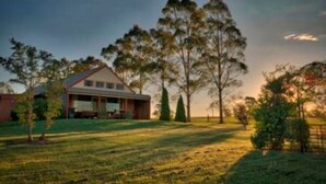 A house with a large lawn and tall trees in the background. - Bluebush Estate (Lovedale)