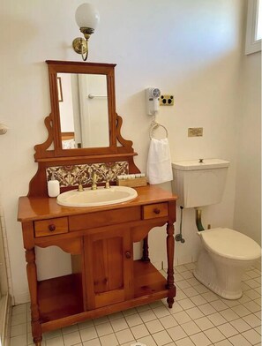 Bathroom features a round sink, mirror, and toilet, with a towel rack and wall-mounted hairdryer.