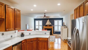 A modern kitchen with wooden cabinets, a built-in dishwasher, and a large island. - Coastal Beauty-Bike to Beach (Lewes)