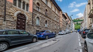 Une rue bordée de voitures garées et d’immeubles historiques en pierre.