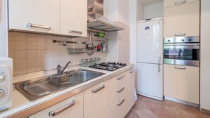 Une cuisine équipée d’une cuisinière à gaz, d’un évier, d’appareils électroménagers en acier inoxydable et de meubles de couleur beige.