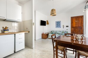 A kitchen with white cabinets, a wooden countertop, and a dining area with a table and chairs.