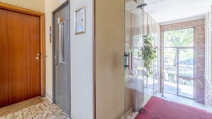 Entrada de hotel con puerta de madera, puerta de vidrio, alfombra roja y vista al exterior.