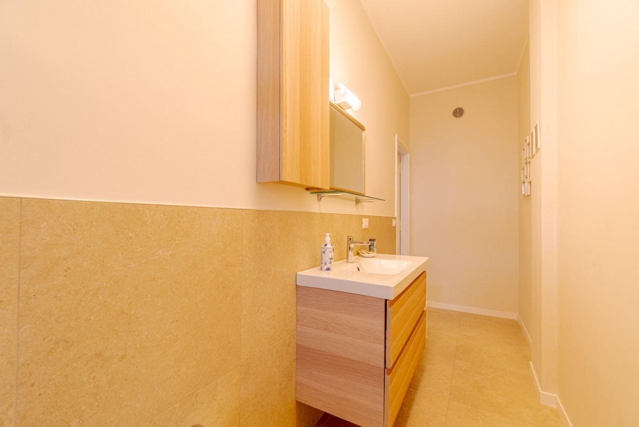 A bathroom with a wooden vanity, a mirror, and a sink.