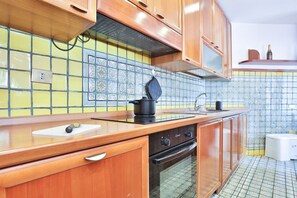Een keuken met houten kastjes, een fornuis en een betegelde spatwand.