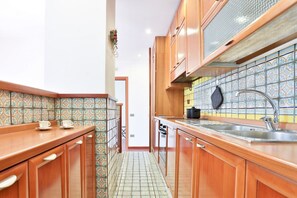 A kitchen with wooden cabinets, a tiled backsplash, and a stainless steel sink.