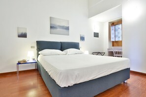 A bedroom with a bed, bedside tables, a desk, and artwork on the walls.