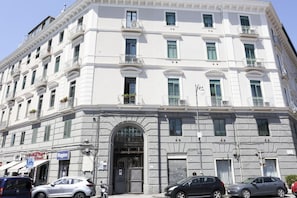 A multi-story building with a central entrance, balconies, and a ground-level shop.