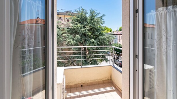 Un balcón con vistas a edificios y árboles.