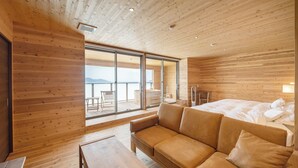 A modern wooden interior with a sofa, a table, and a bed. - genkairyokan (Munakata)