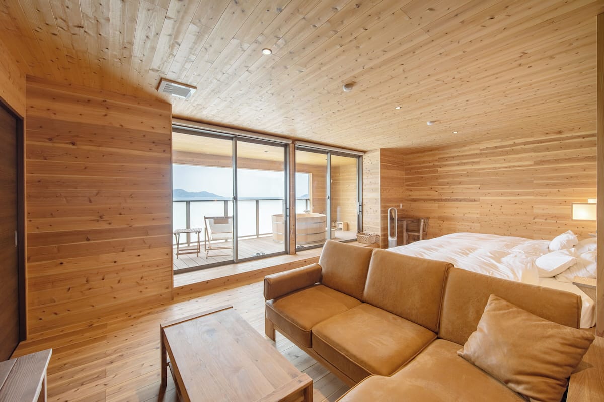 A modern wooden interior with a sofa, a table, and a bed.