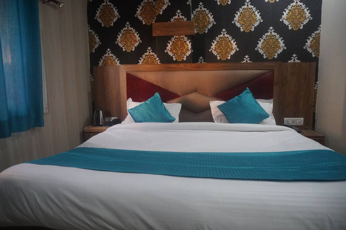 Een hotelkamer met een groot bed, een houten hoofdeinde en behang met een patroon.
