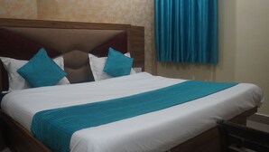 A bed with a wooden headboard, white bedding, and teal accents. - Hotel Rudreshwar (Haridwar)