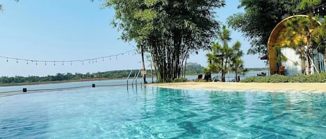 Una piscina al aire libre, sombrillas, sillones reclinables de piscina