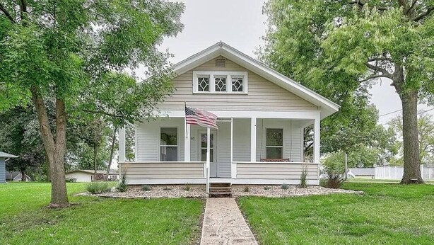 A single-story house with a front porch, a small front yard, and a pathway leading to the entrance. - New Kitchen,FirePit,FamFriendly,Sleeps10:LakeLux (Arnolds Park)